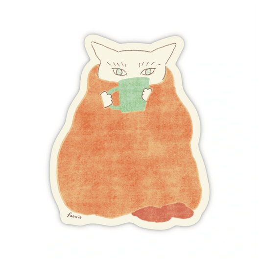 A die-cut sticker of a cute illustration of a white cat wrapped in a warm orange blanket and holding a green mug, shown on a plain white background.