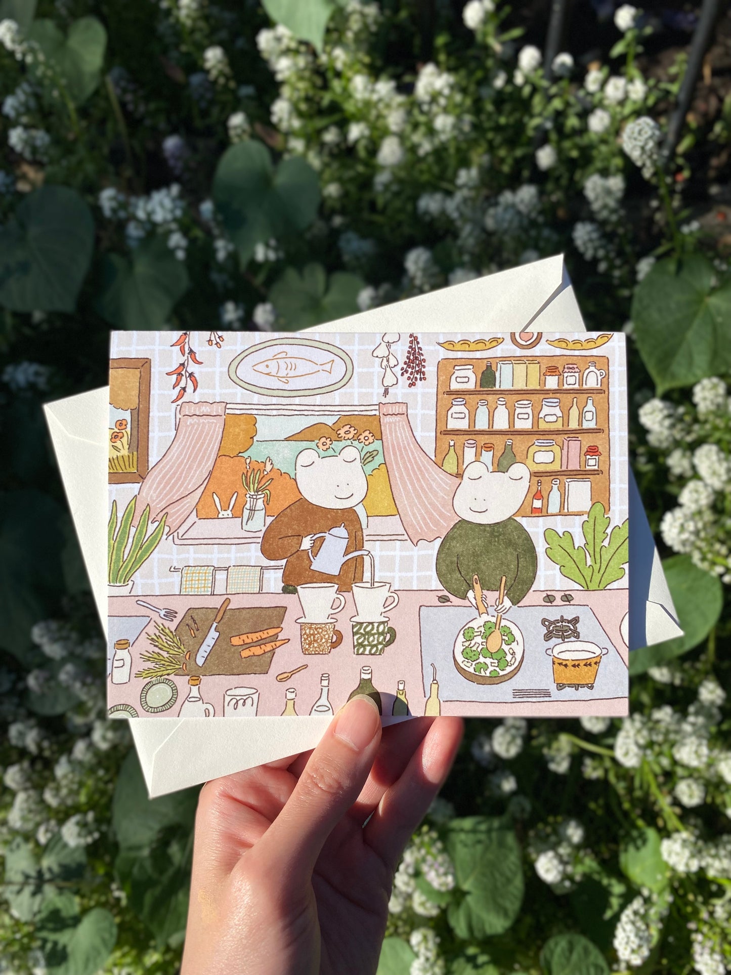 Illustrated card held by a hand with a garden background