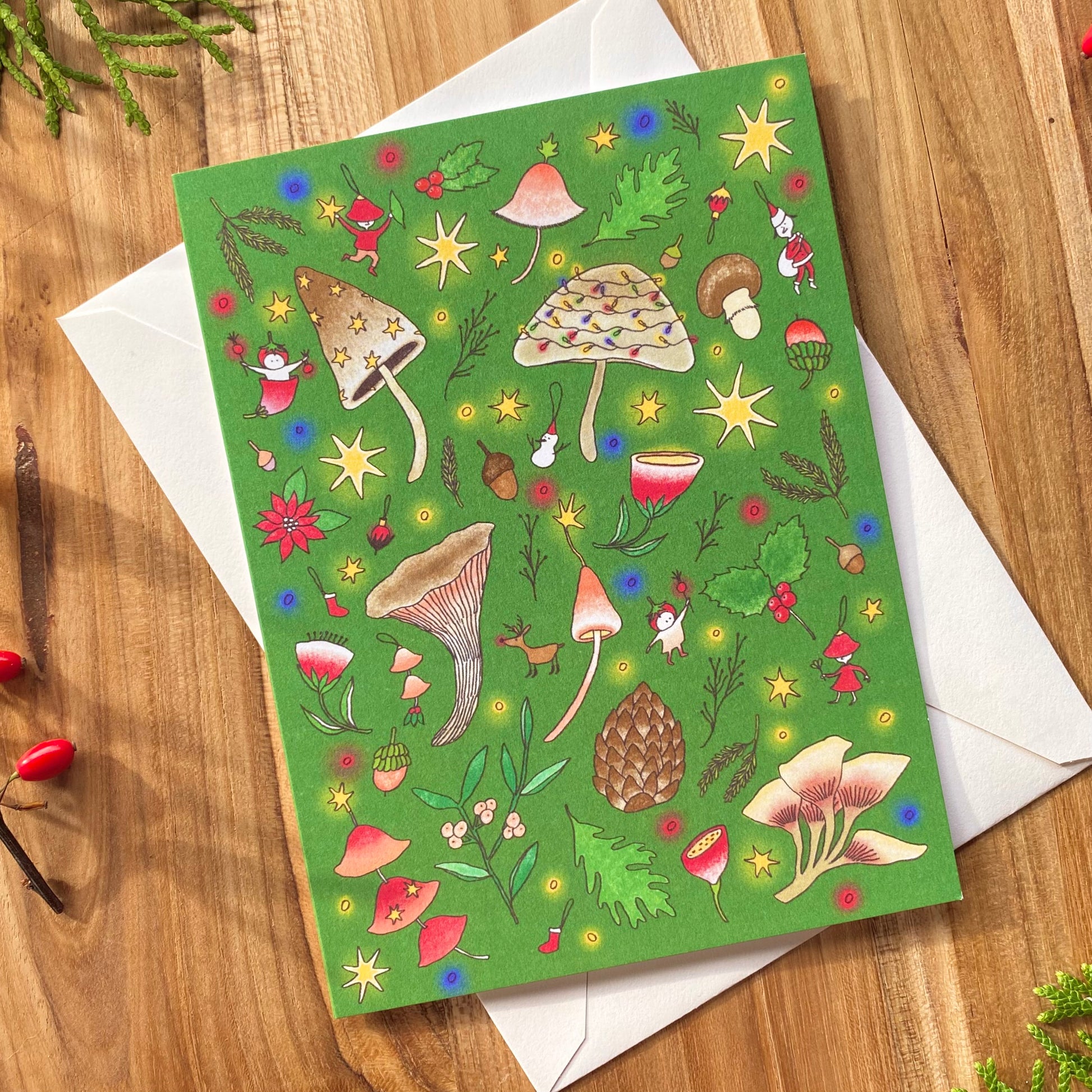 Green greeting card with mushroom-themed illustrations on a wooden table