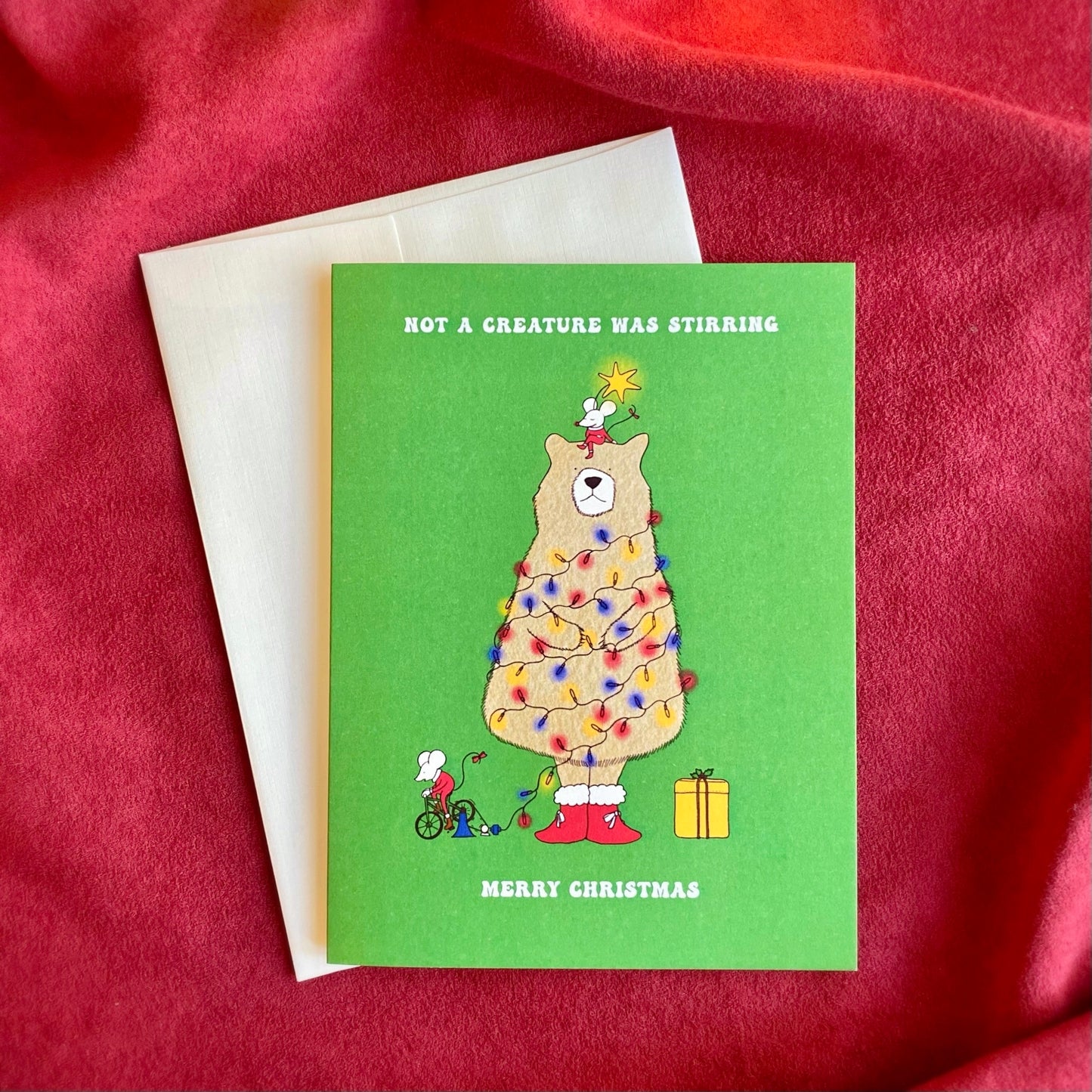 Cute Christmas Card with the text “not a creature was stirring, Merry Christmas” and the illustration of a bear as a Christmas tree and two mice on a green background