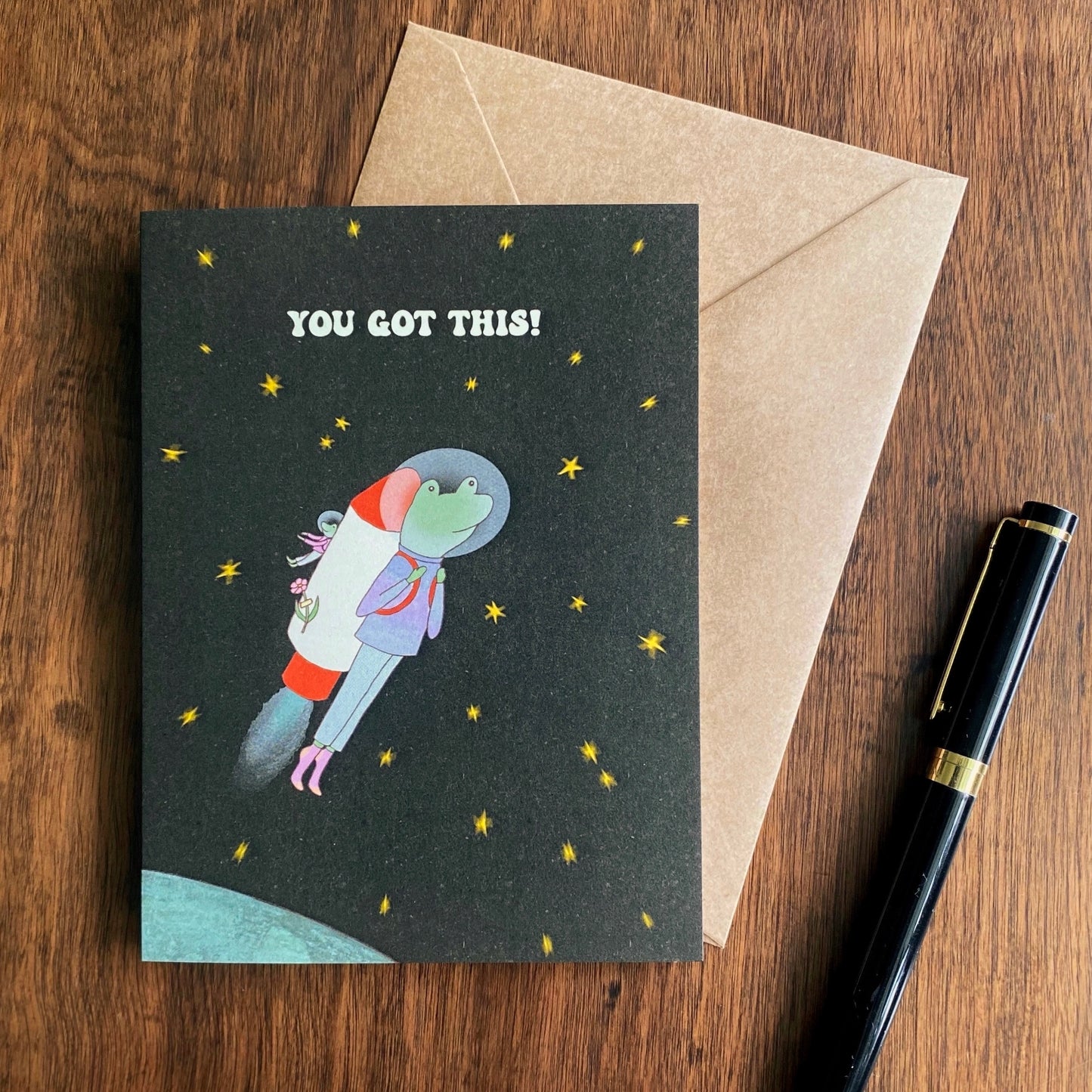 Cute Good luck Card with the illustration of a frog as an astronaut heading to the universe with a rocket machine on his back
