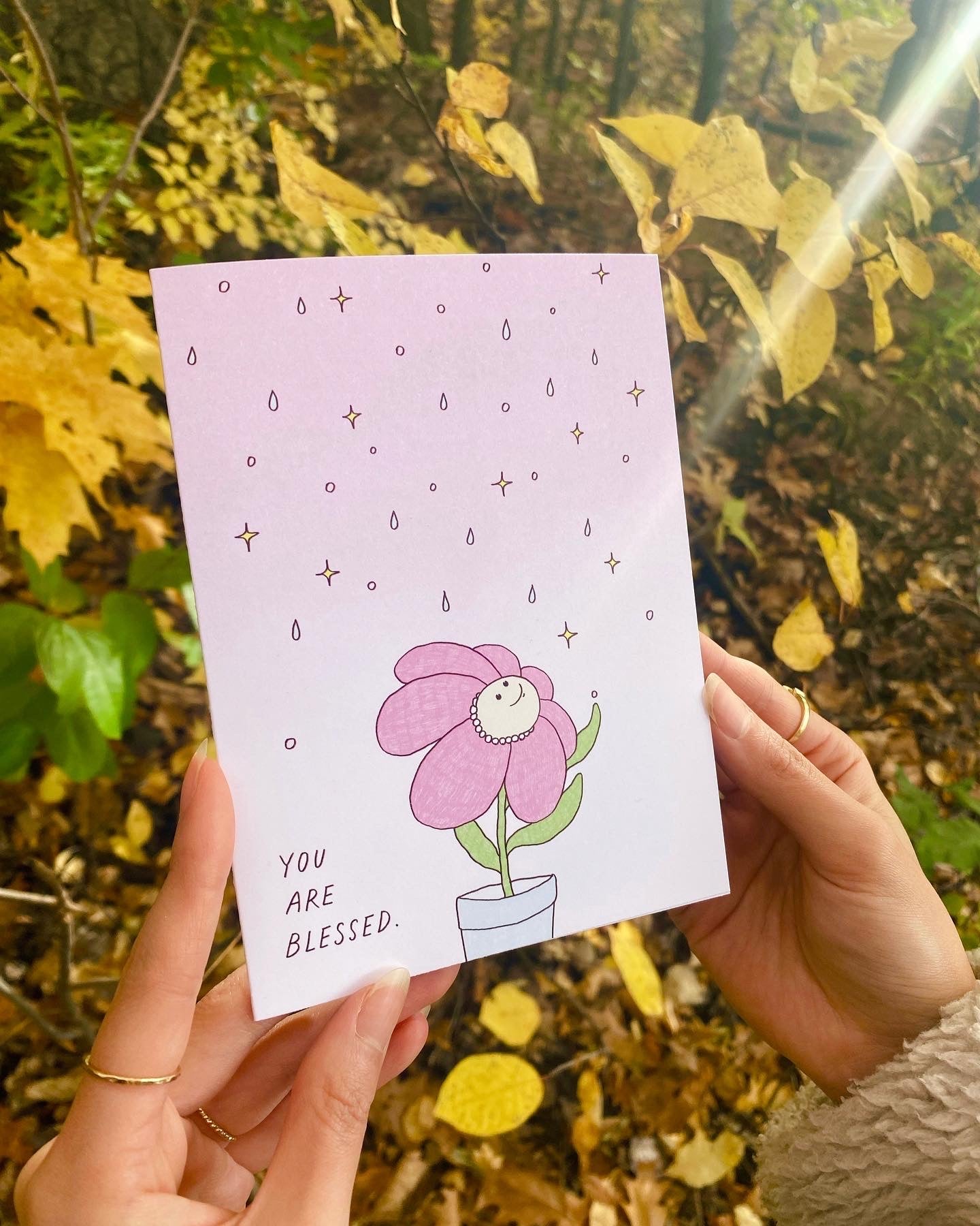 Motivational just because card that says “You Are Blessed” with the illustration of a happy pink flower being blessed by sparkly pink sky