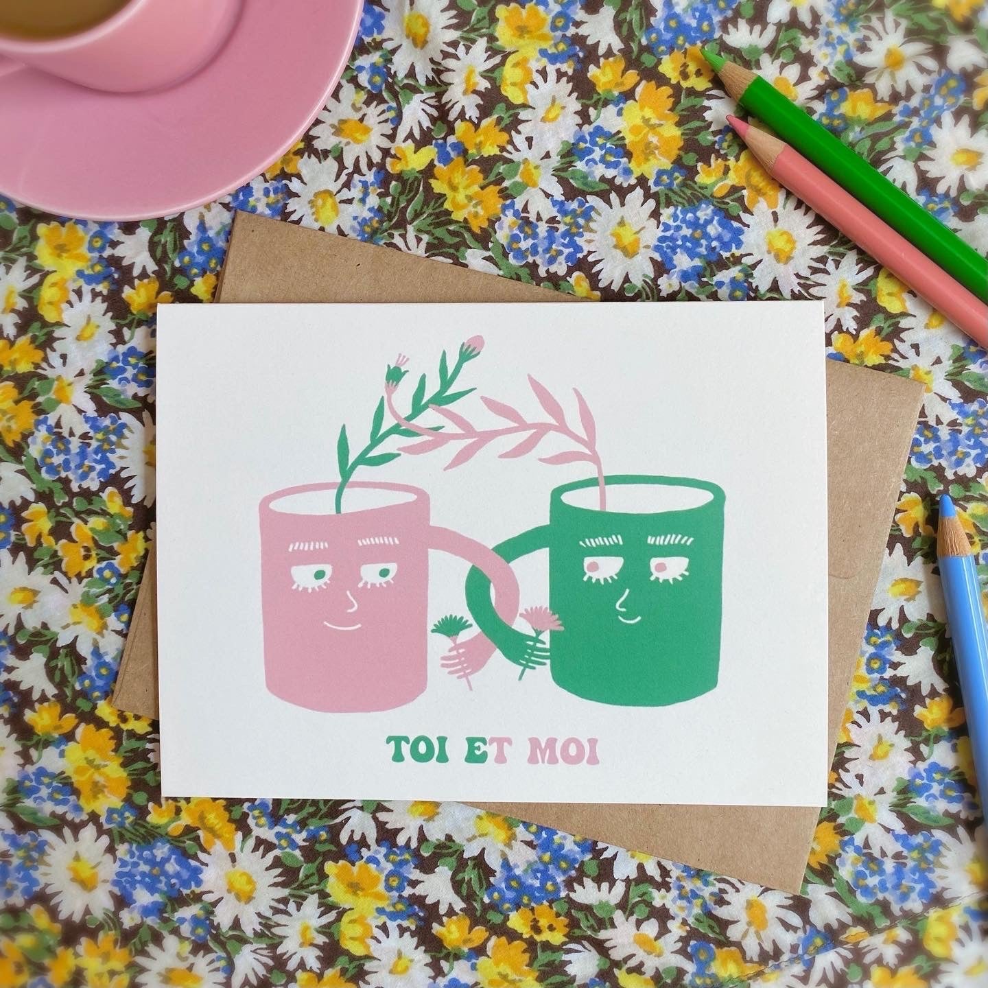 Cute love and friendship card with the illustration of two mugs looking at each other while their handles are intertwined